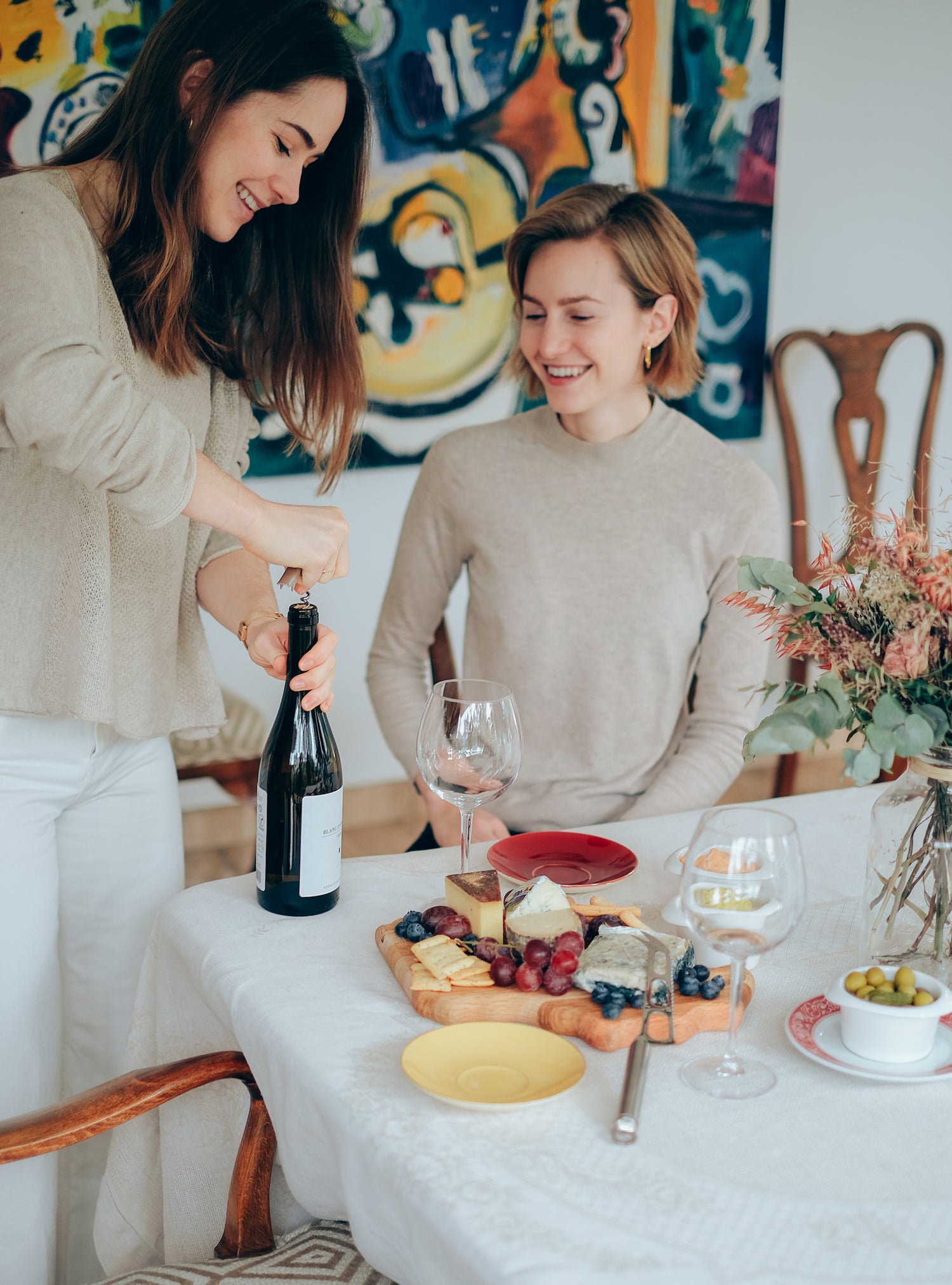 Alba y Sofía descorchando una botella de vino para un aperitivo
